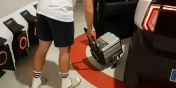 persona conectando un cargador portatil a un coche sin carnet en un garaje