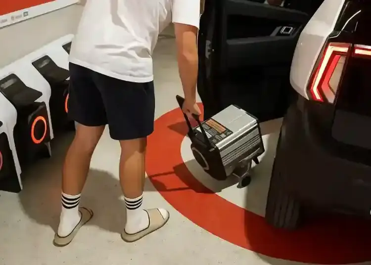 persona conectando un cargador portatil a un coche sin carnet en un garaje