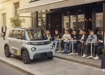 fotografia real del citroen ami electrico aparcado en una calle urbana junto a una terraza con varios jovenes